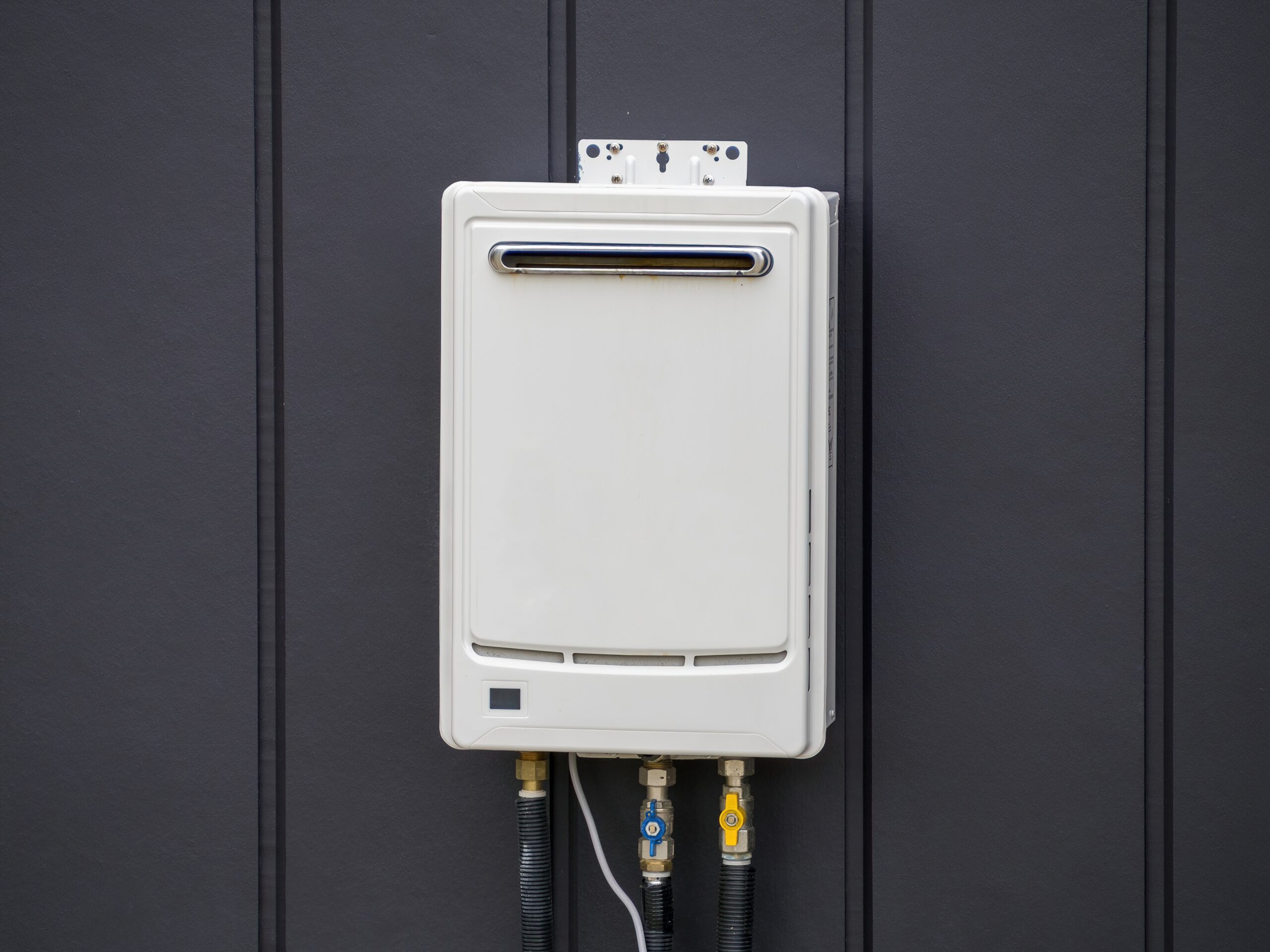 White,Tankless,Gas,Water,Heater,Installed,On,Dark,Vertical,Panel tankless water heater mounted on black wall
