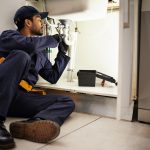 Plumber working under sink