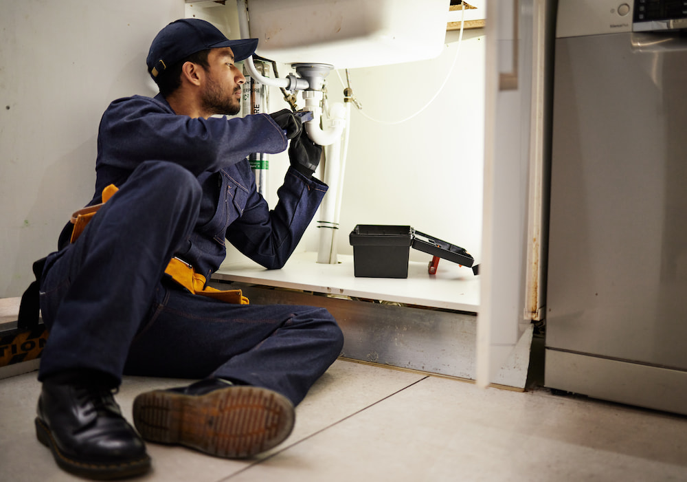 Plumber working under sink